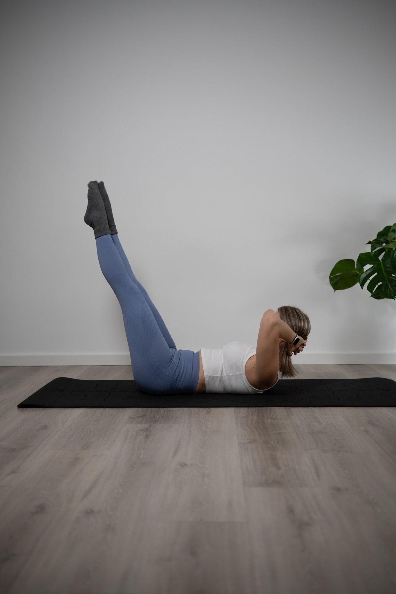 Matten-Pilates Übung: Sara liegt auf der Matte mit gestreckten Beinen in der Luft