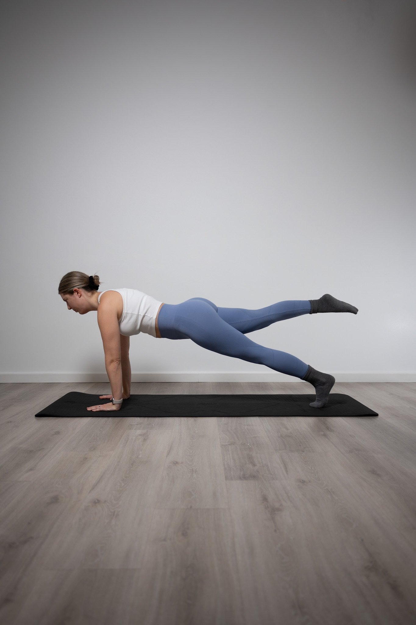 Pilates Plank-Variation mit einem in die Luft gestreckten Bein